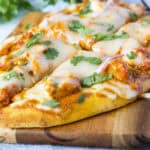 cropped close up sliced chicken tikka pizza on cutting board