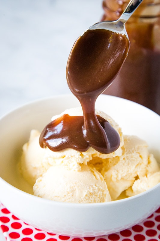 homemade chocolate sauce spooned over vanilla ice cream