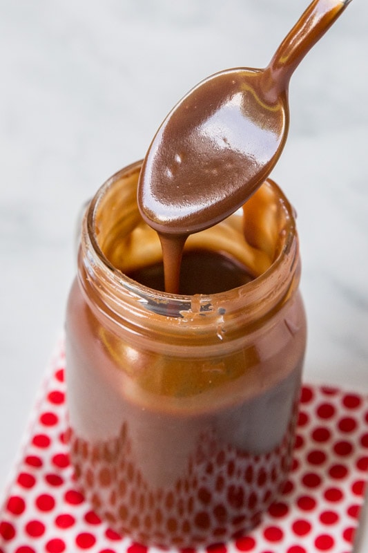 Super thick and rich hot fudge sauce in glass jar with spoon