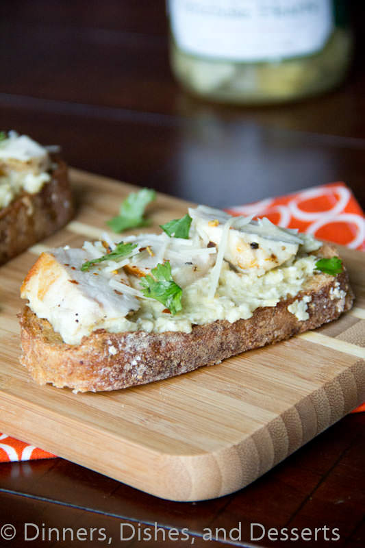 open faced chicken sandwich with artichoke pesto on a board