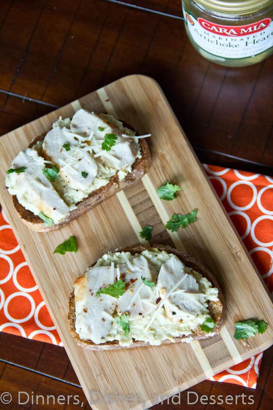 open faced chicken sandwich with artichoke pesto on a board