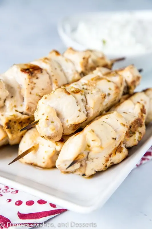 Chicken Souvlaki skewers on a white plate with homemade tzatziki sauce