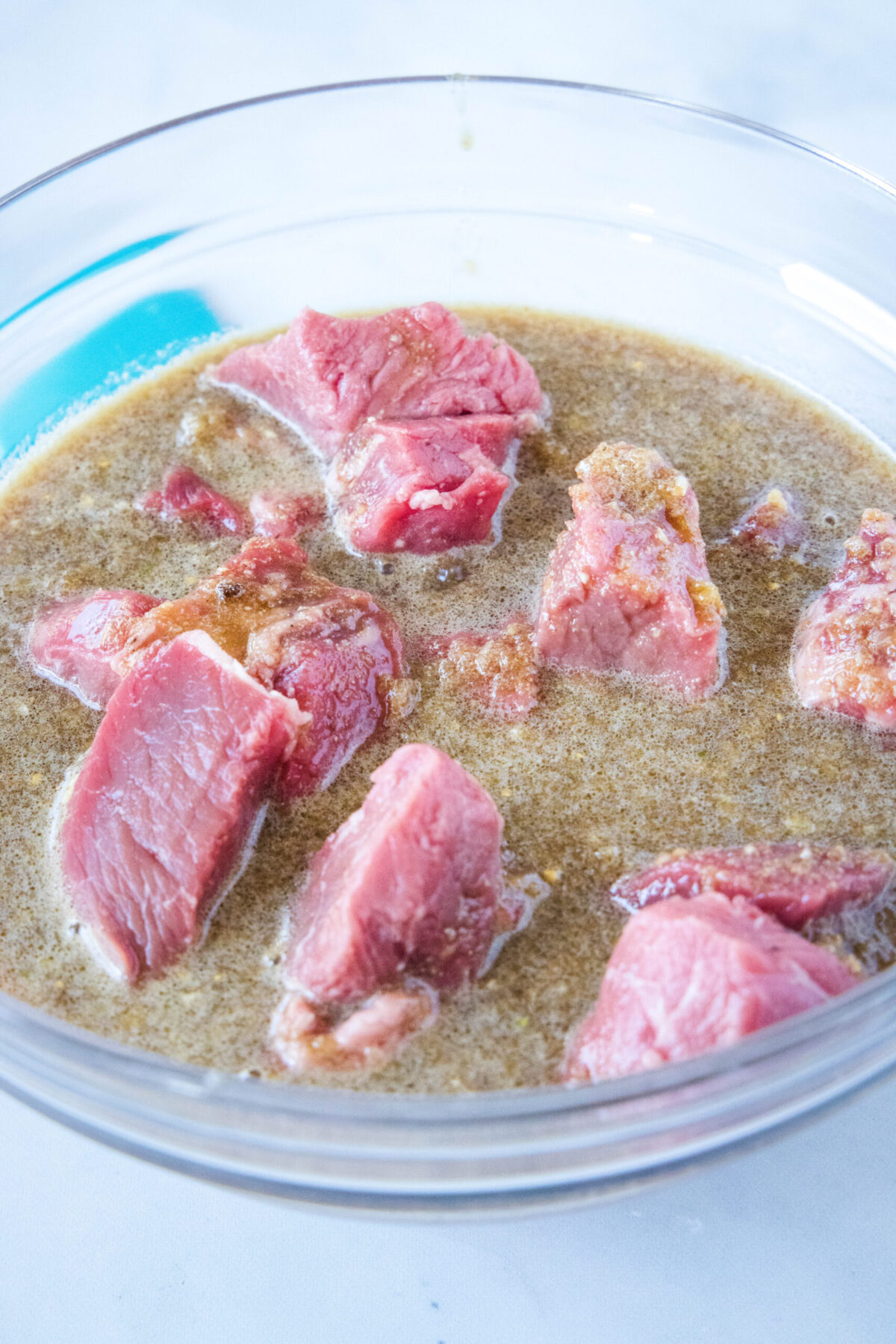 Cubes of beef in a mixing bowl with marinade