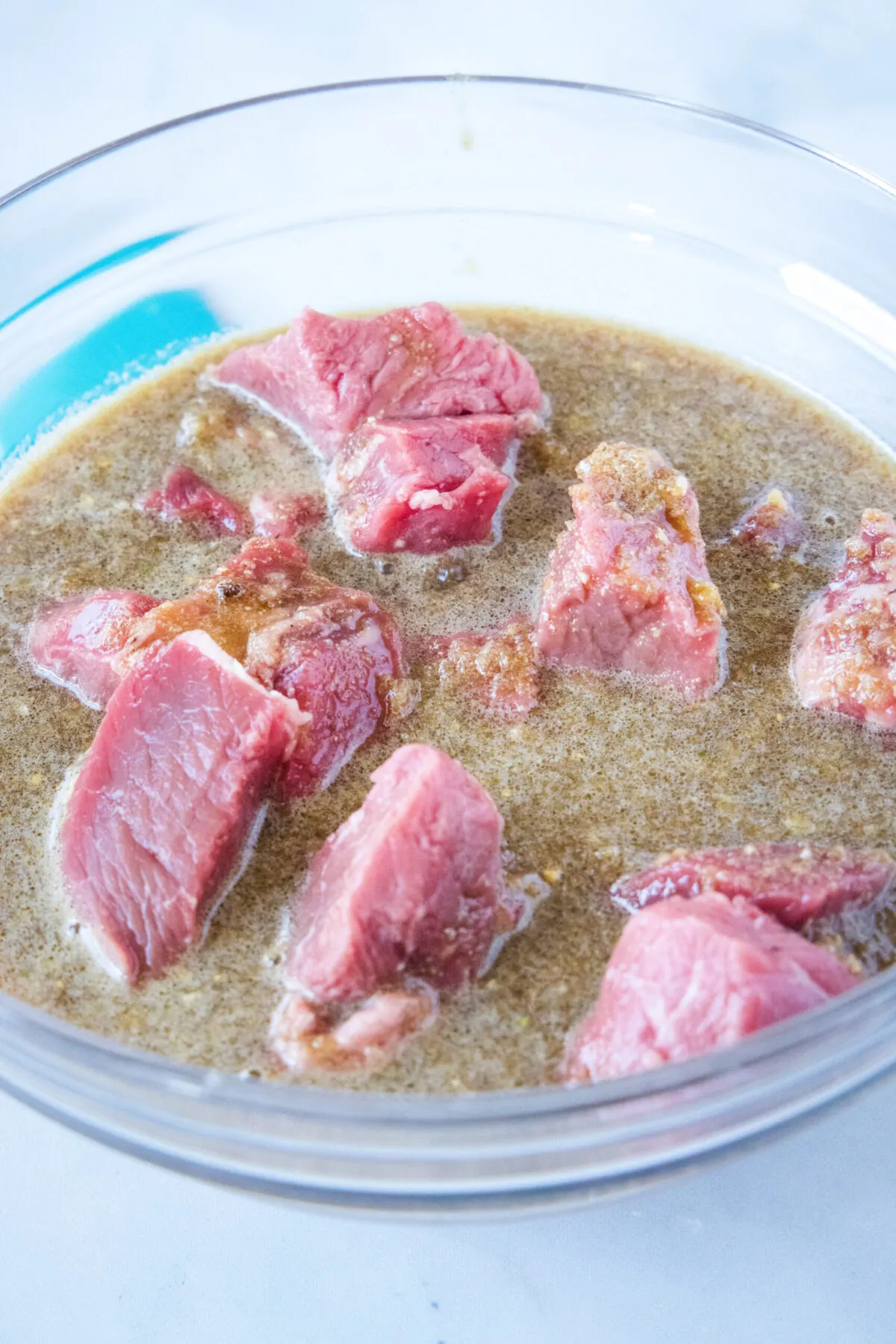 Cubes of beef in a mixing bowl with marinade