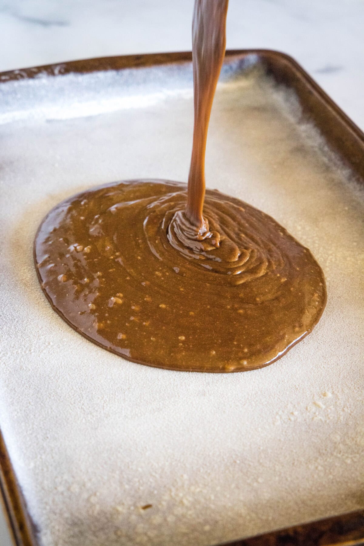 pouring cake batter into sheet pan
