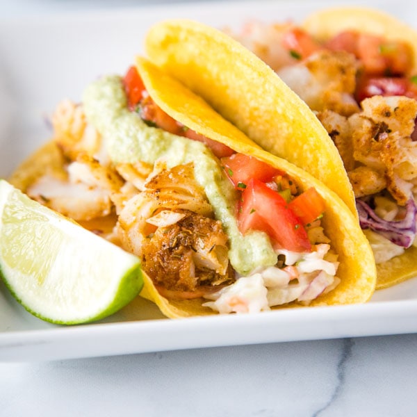 A plate of fish tacos with different toppings, with Taco
