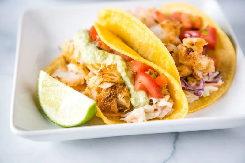 Easy Fish Tacos - a super easy, healthy, and delicious cod fish taco recipe.  Topped with a fresh Mexican coleslaw, pice de gallo, and a roasted poblano fish taco sauce. 