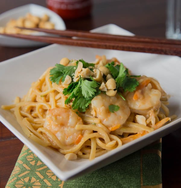 shrim pasta in a white bowl topped with cilantro and peanuts