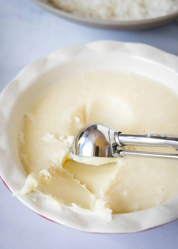 A cookie scoop scooping balls of white chocolate truffle from a bowl