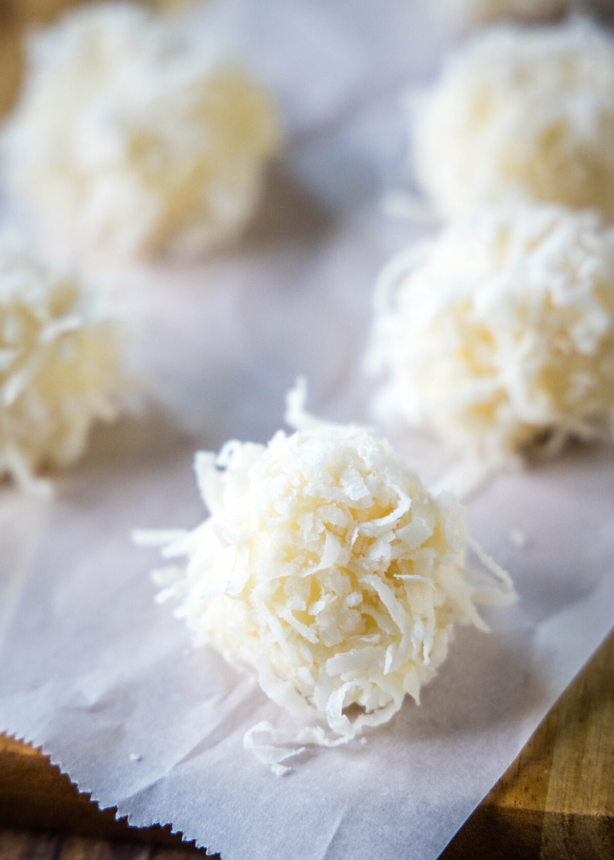 White chocolate truffles covered in coconut on a piece of parchment paper