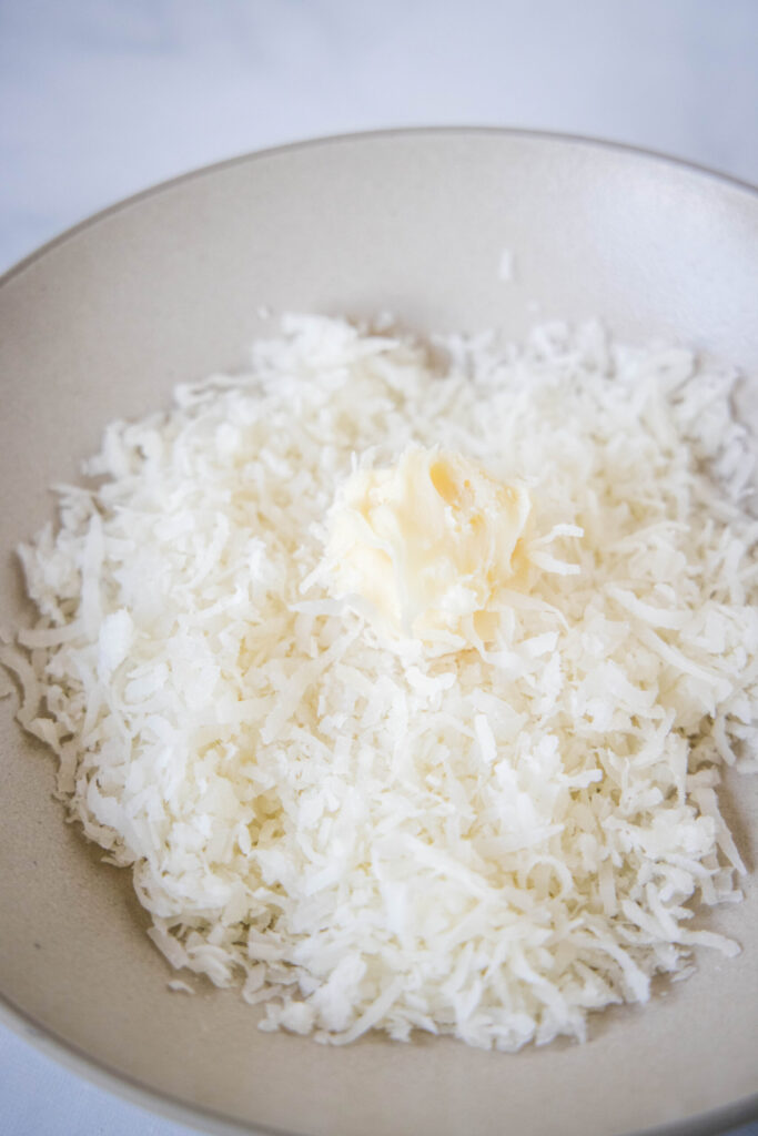 A white chocolate truffle in a bowl of shredded coconut
