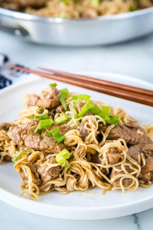 white plate with pork lo mein and chop sticks