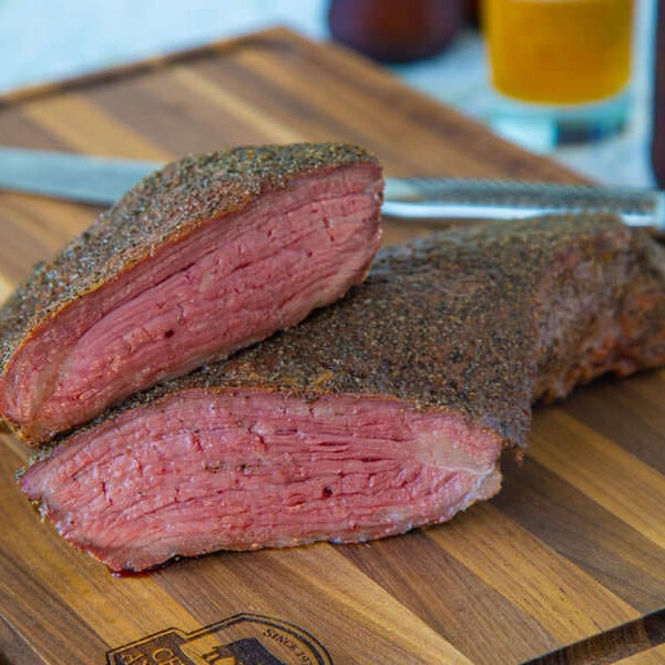 A piece of meat sitting on top of a wooden cutting board, with Tri-tip
