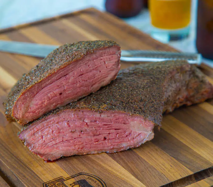 A piece of meat sitting on top of a wooden cutting board, with Tri-tip