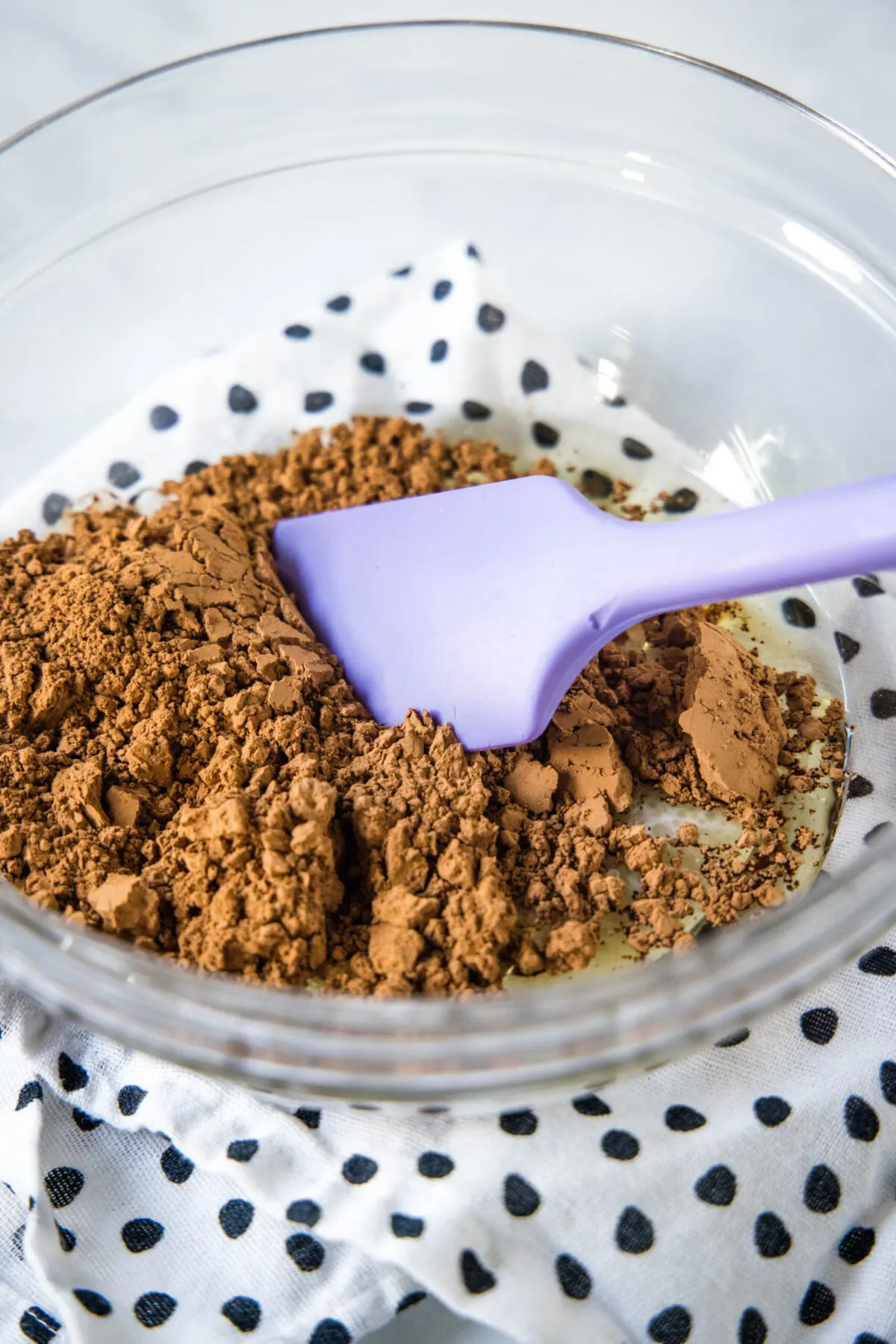 A mixing bowl with cocoa powder and a rubber spatula.