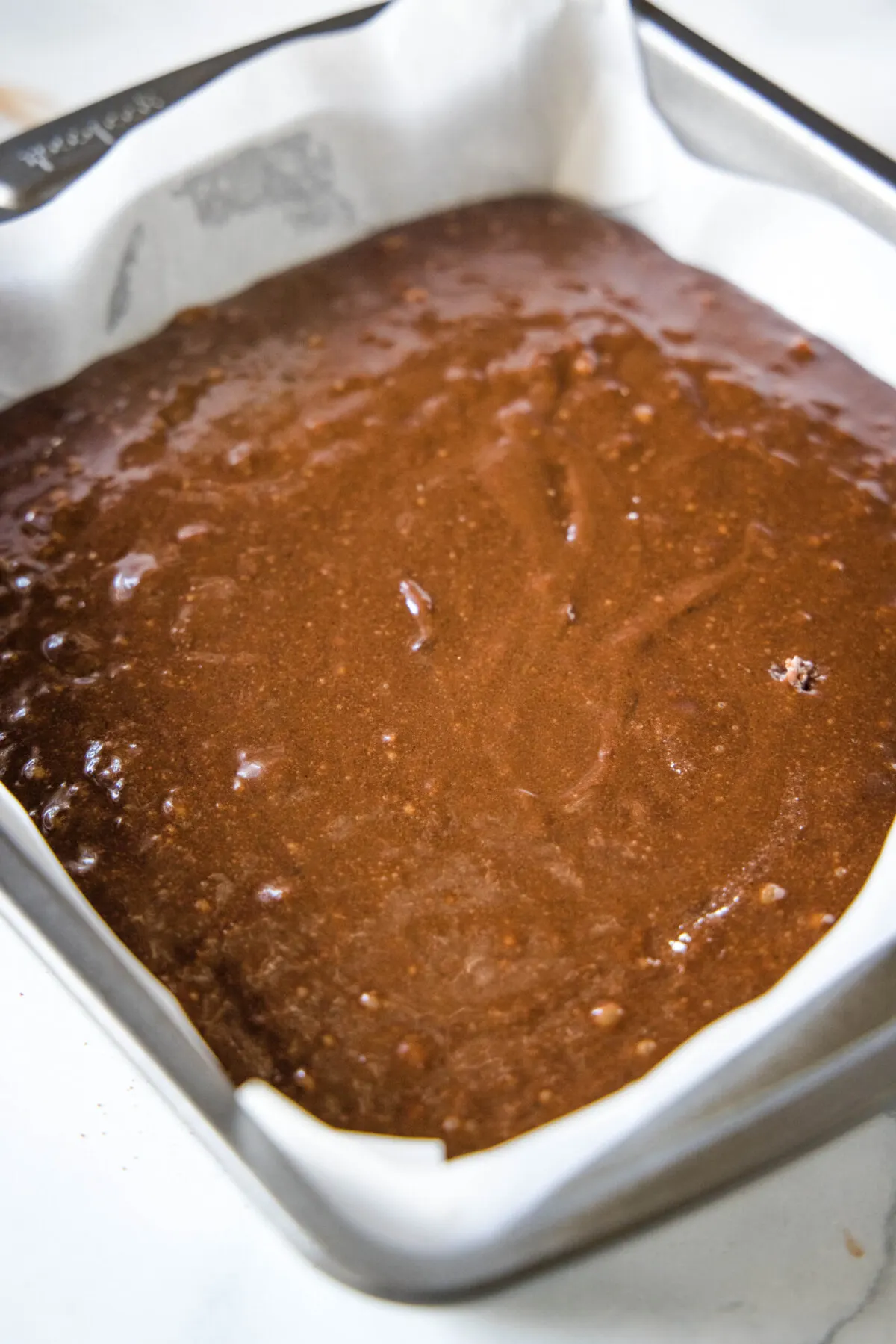 A square baking dish filled with brownie batter.