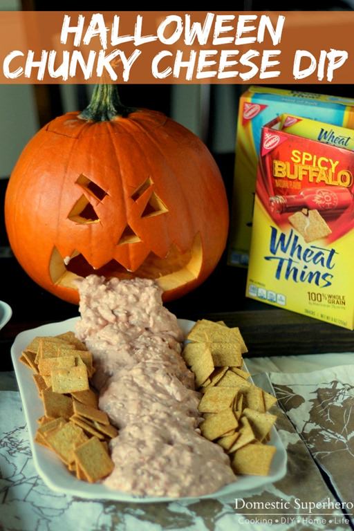 Angled view of halloween dip pouring out of a pumpkins mouth with spicy buffalo wheat things box on the side.