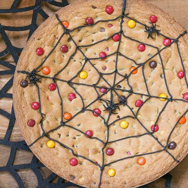 Above view of a spider web cookie cake with candy and chocolate.