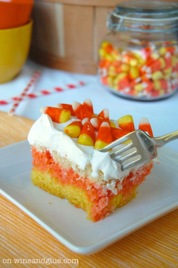 Close up view of a candy corn cake being cut with a fork.