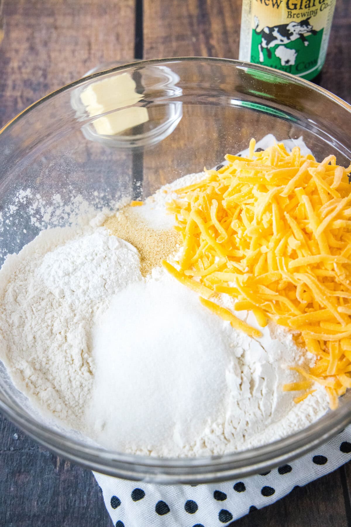 A mixing bowl filled with flour, cheese, salt, sugar, baking powder, and garlic powder