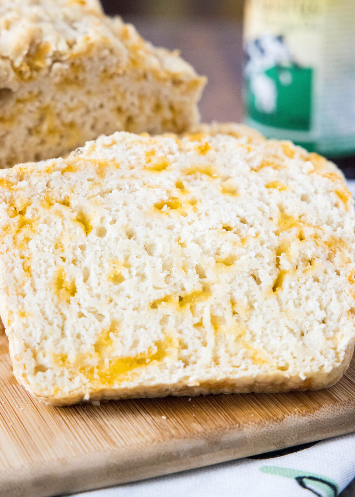 Close up of a slice of beer bread with a loaf in the background