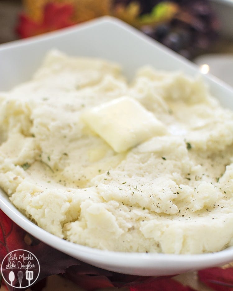Close up view of mashed potatoes in a bowl with a butter square on top.
