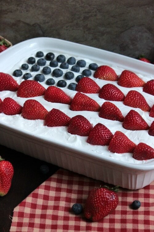 USA Flag Eclair Cake in a white ceramic dish on a checked napkin