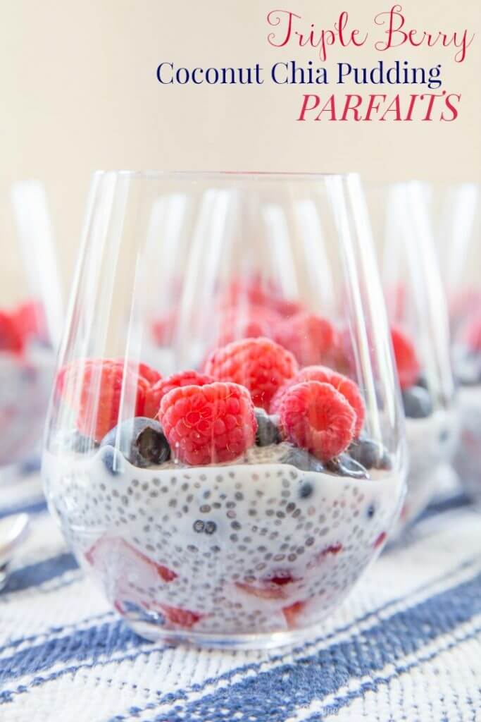 Triple Berry Coconut Chia Pudding Parfaits in clear glasses on a blue and white striped napkin