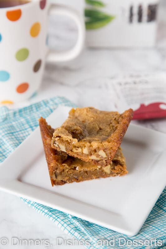 A piece of cake on a plate next to a cup of coffee, with Tea and Nut