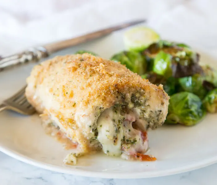 Italian Stuffed Chicken - chicken breasts rolled up with pesto, tomatoes, and cheese! Then baked until crispy and delicious, a great family dinner.