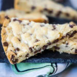 Close up of a triangle of chocolate chip shortbread, with more pieces in the background.