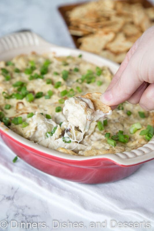 Cheesy Artichoke dip in a bowl with a chip
