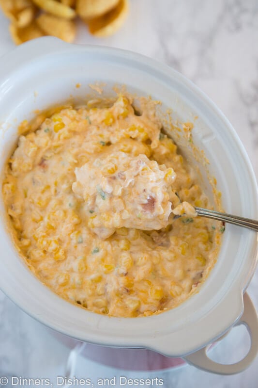 corn dip in a slow cooker with serving spoon