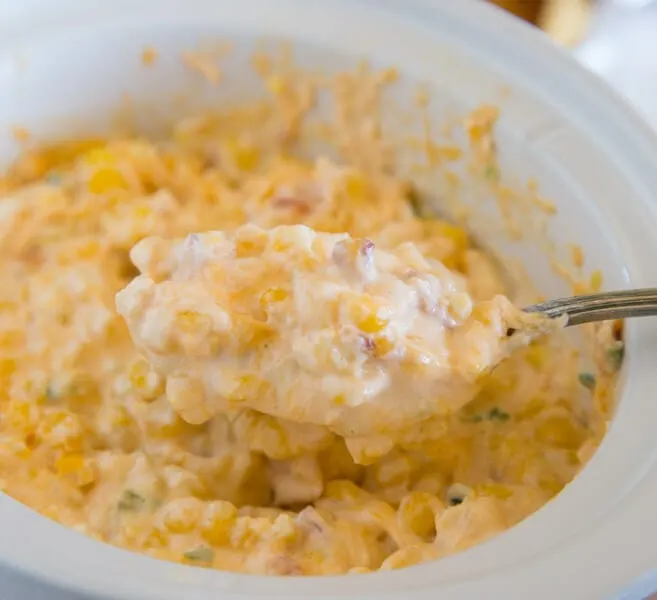 corn dip in a slow cooker with serving spoon