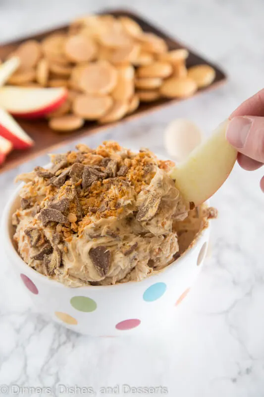 Peanut Butter Butterfinger dip in a bowl with an apple slice