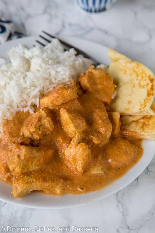 A close up of a plate of food with indian butter chicken and rice