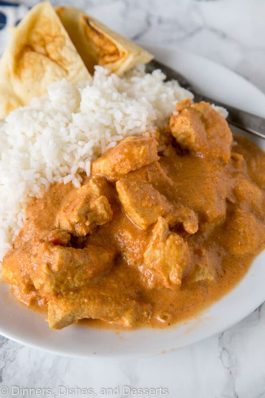 A close up of a plate of food with indian butter chicken and rice