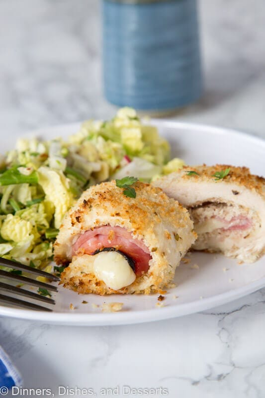 A plate of food on a table, with sliced Cordon bleu and salad