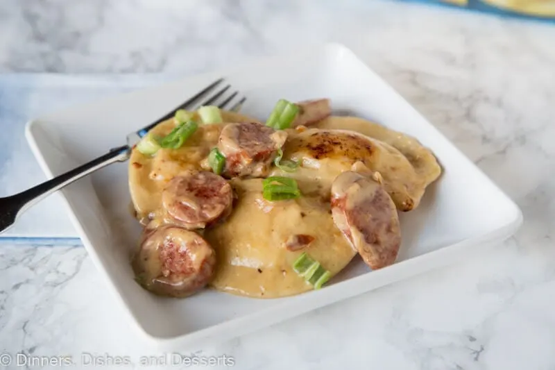 A plate of food with a fork and knife, with Pierogi and Sausage