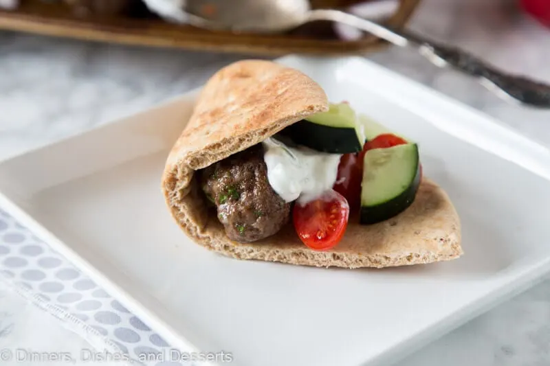 pita filled with meatballs and tzatzki sauce and cucumbers on a plate