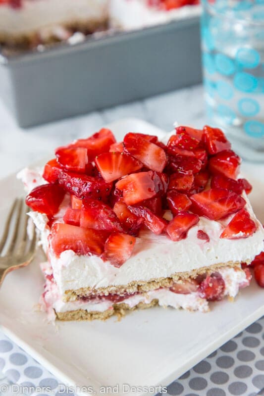 strawberry cheesecake lasagna with fresh strawberries on a plate with a fork