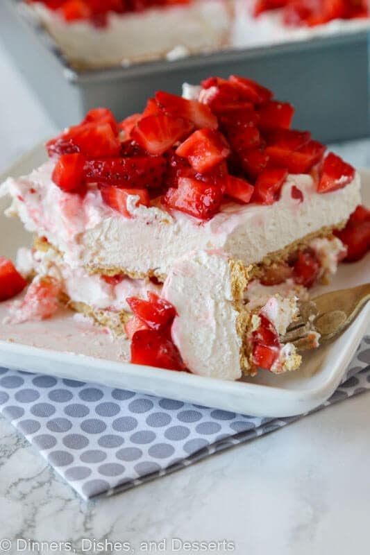 strawberry cheesecake lasagna with fresh strawberries on a plate with a fork