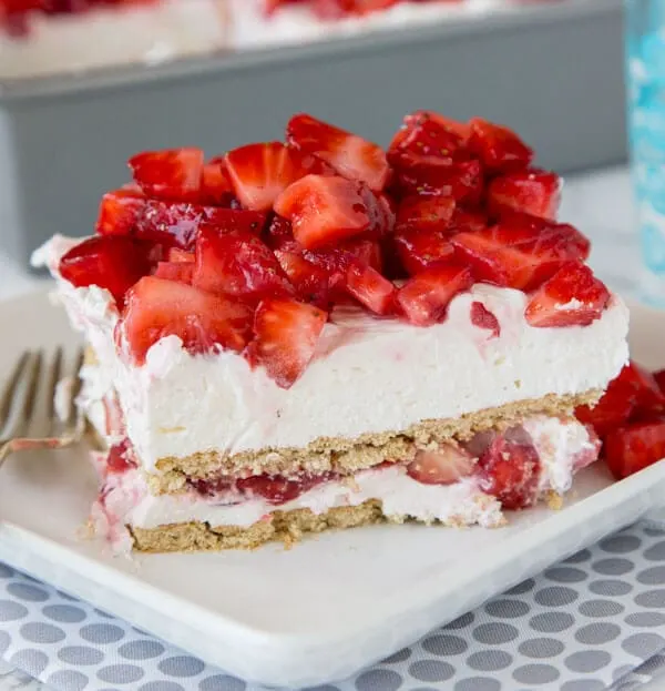 strawberry cheesecake lasagna with fresh strawberries on a plate with a fork