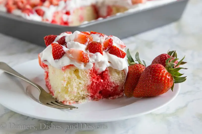 Poke cake with strawberry jello filling the holes and homemade whipped cream on top