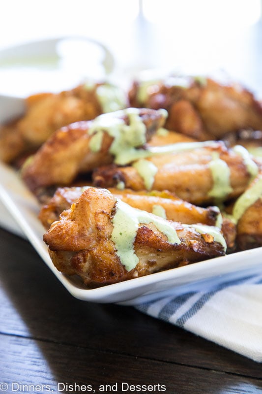 chicken wings on a plate with green sauce on top