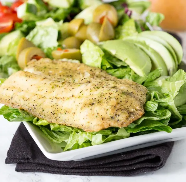 Garlic & Herb Mediterranean Salad - A crisp salad with fresh salad with garlic & herb tilapia and topped with a lemon garlic vinaigrette.