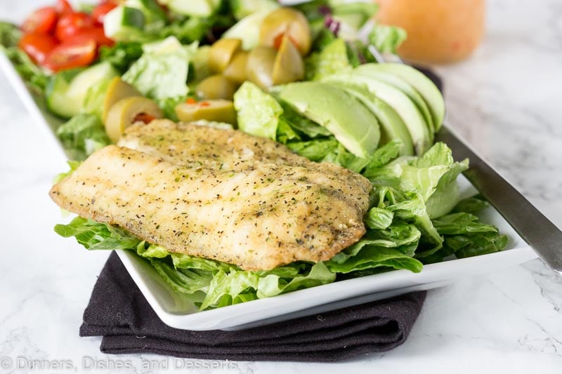 salad on a plate with garlic herb grilled fish on top