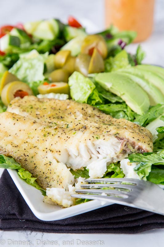 a salad with a piece of fish on top