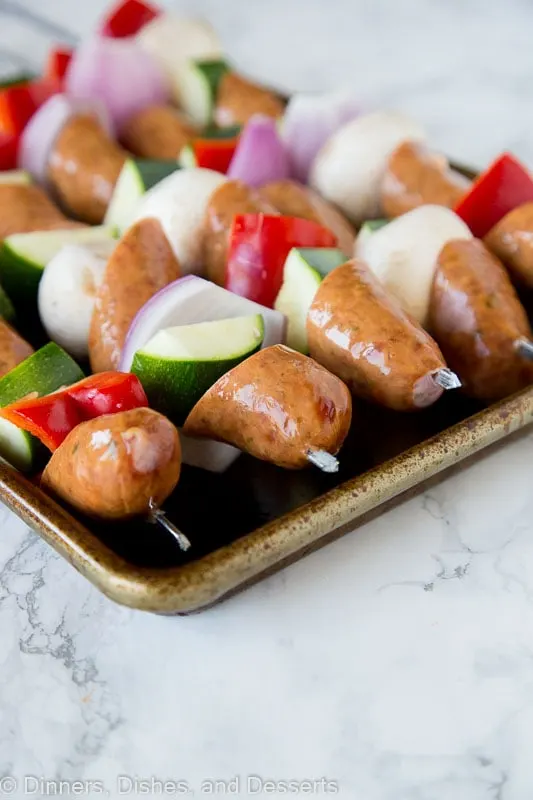 sausage and veggie kebabs before the grill on a tray