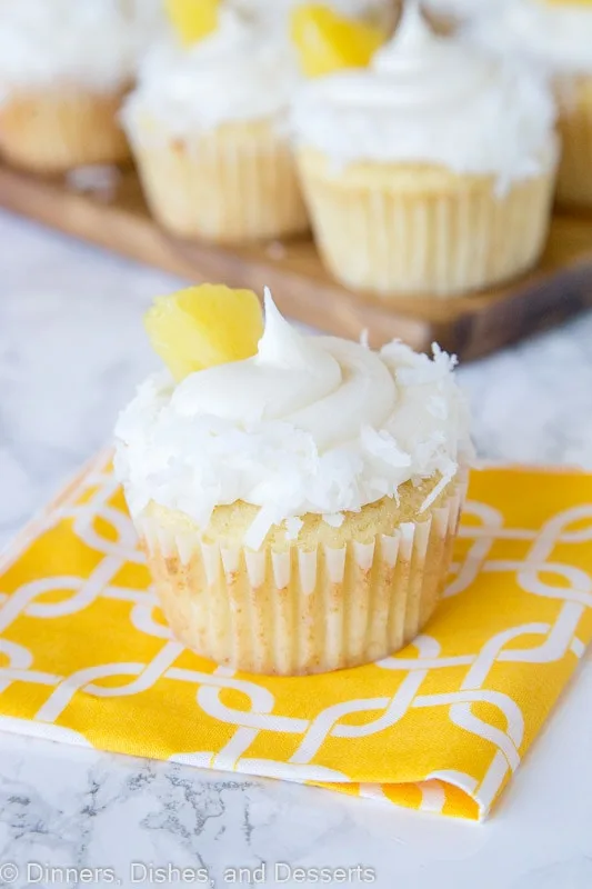 A close up of A close up pineapple cupcakes with coconut and pineapple piece